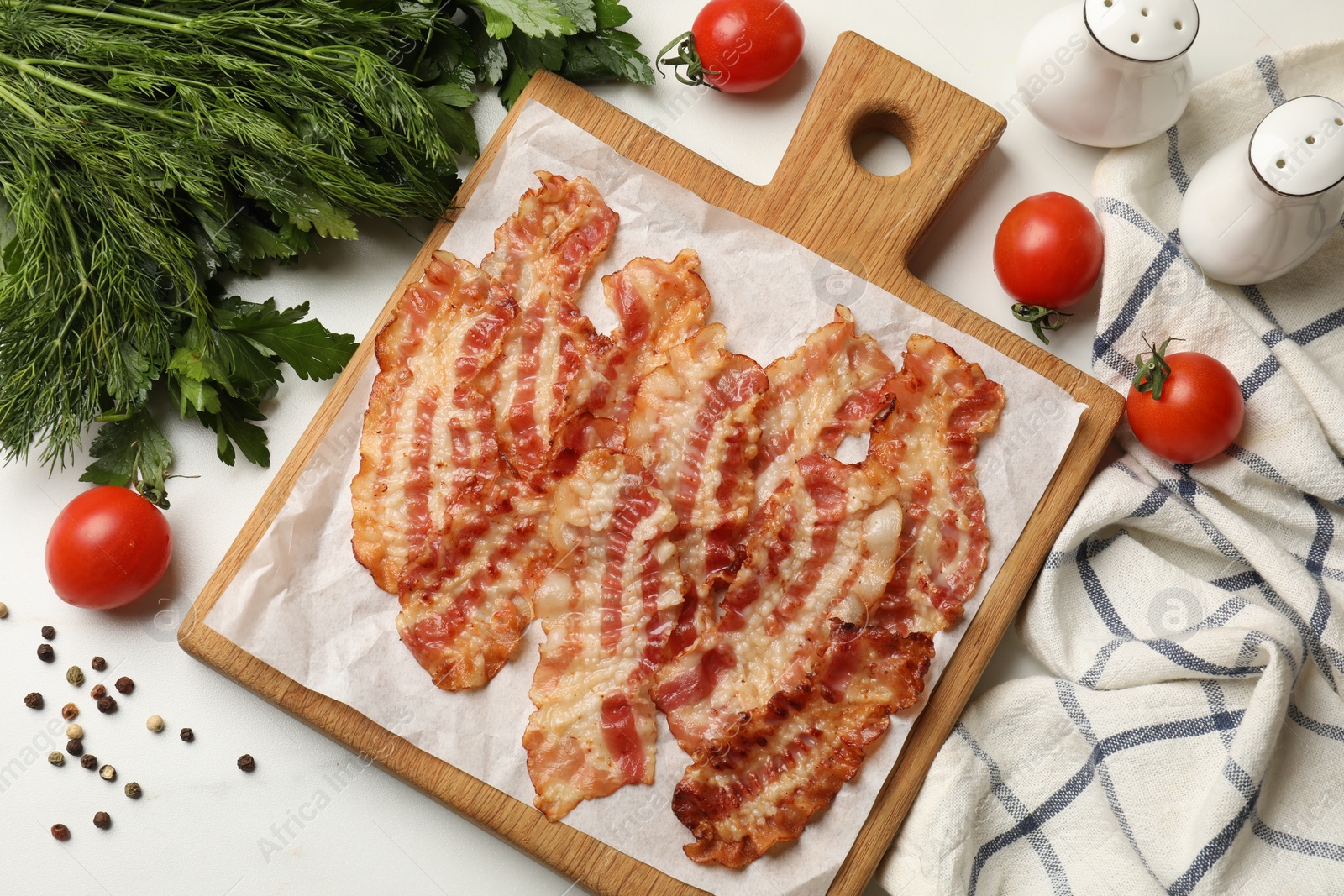 Photo of Delicious fried bacon slices and other products on white marble table, flat lay