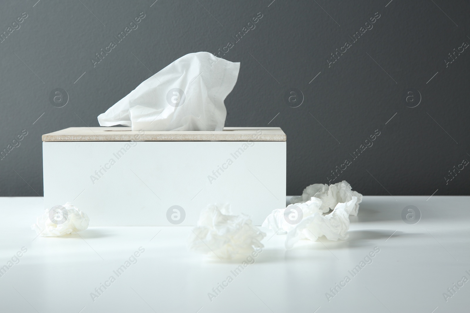 Photo of Used paper tissues and holder on white table