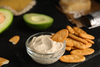 Photo of Delicious crackers and humus on black table, closeup