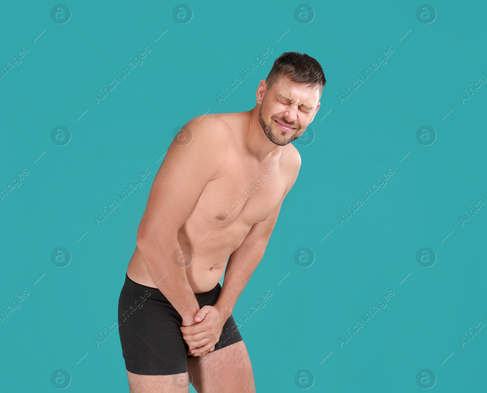 Photo of Man suffering from pain on turquoise background. Urology problems