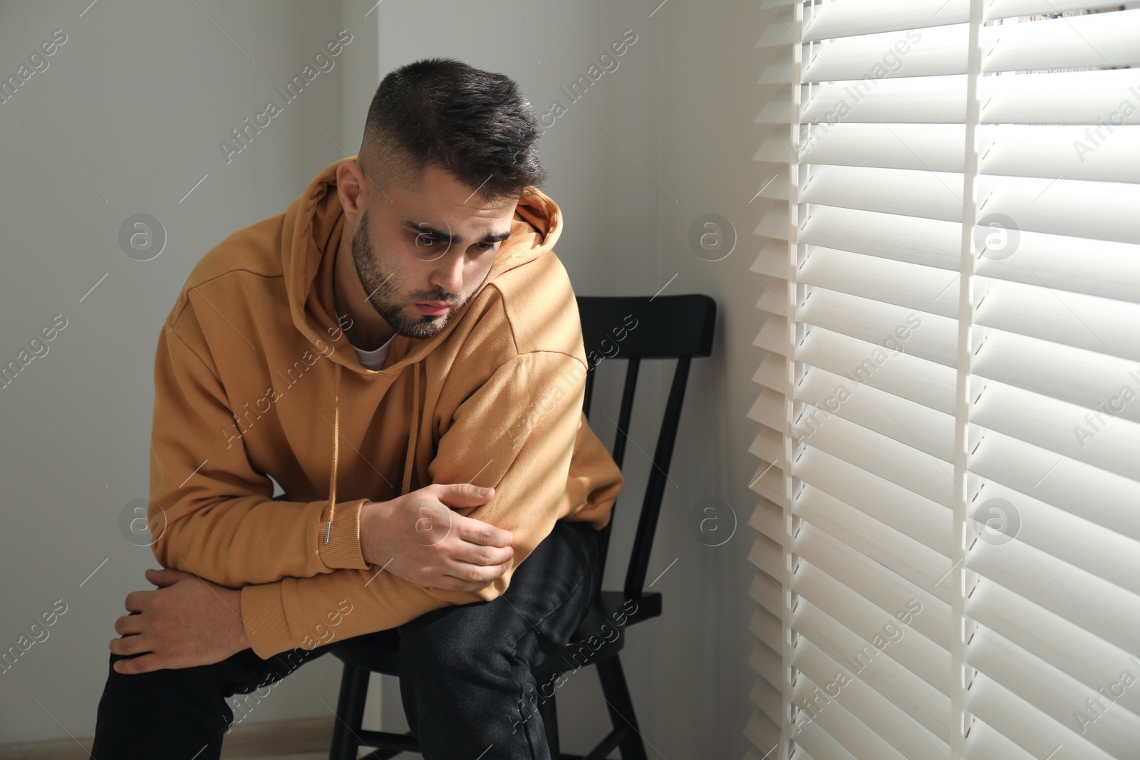 Photo of Sad man sitting on chair near window