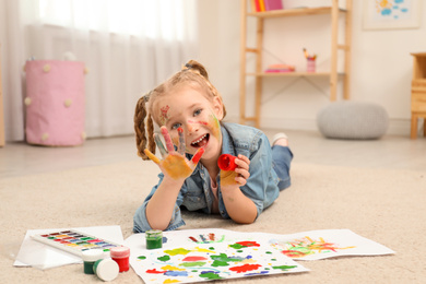Photo of Cute little child painting with palms at home