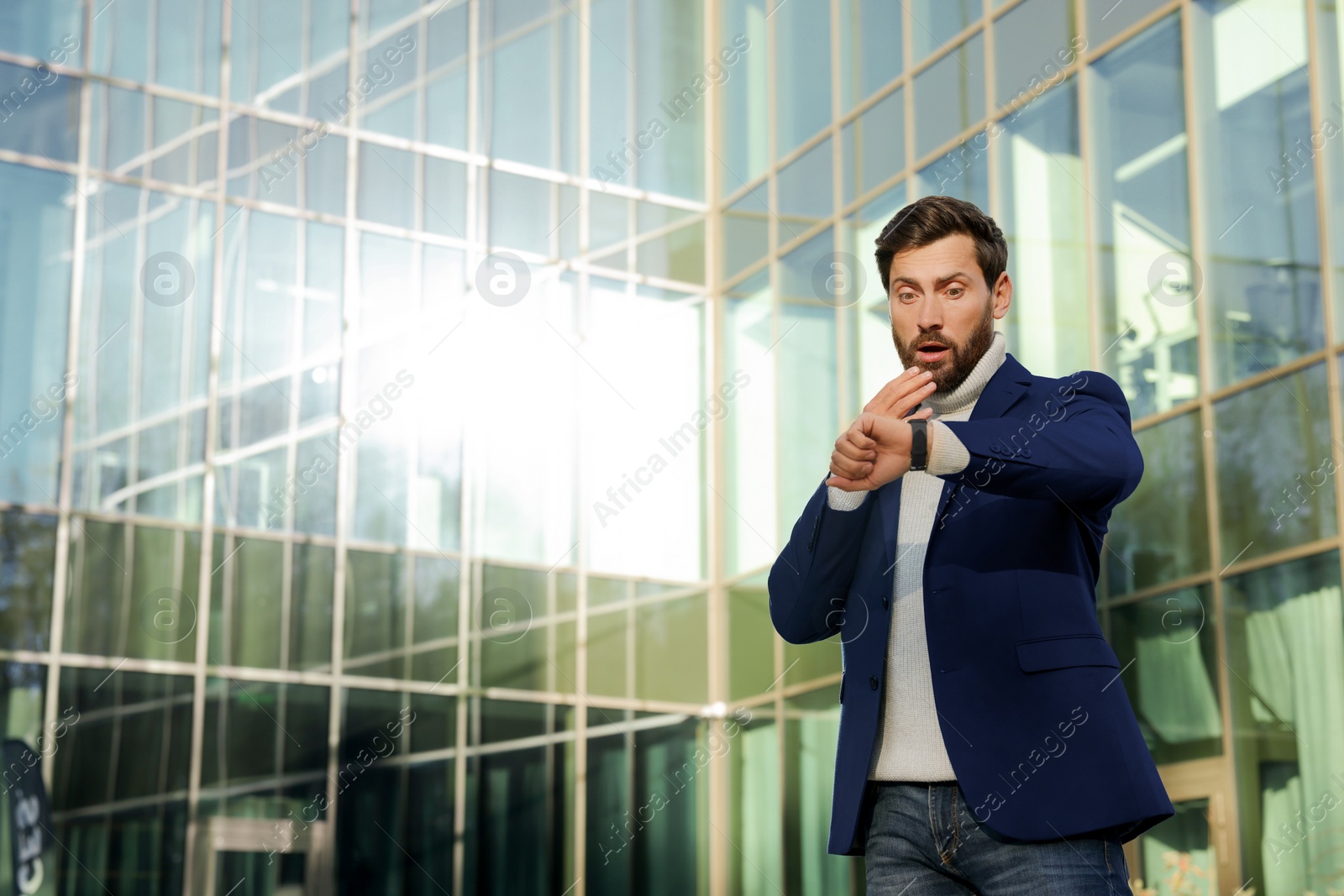 Photo of Businessman checking time on watch near building. Being late concept