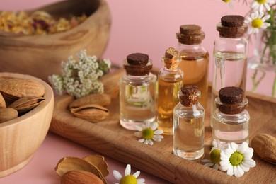 Photo of Aromatherapy. Different essential oils, flowers and almonds on pink background