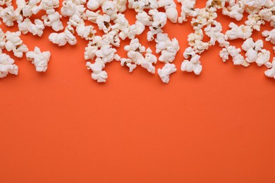 Tasty popcorn scattered on orange background, space for text