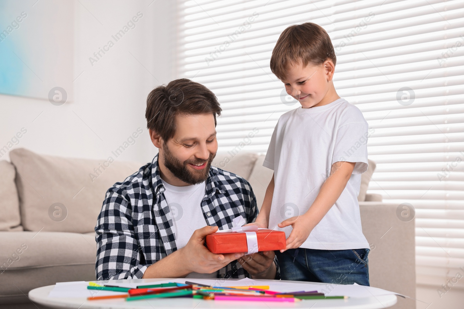 Photo of Happy dad receiving gift for Father's Day from his son at home