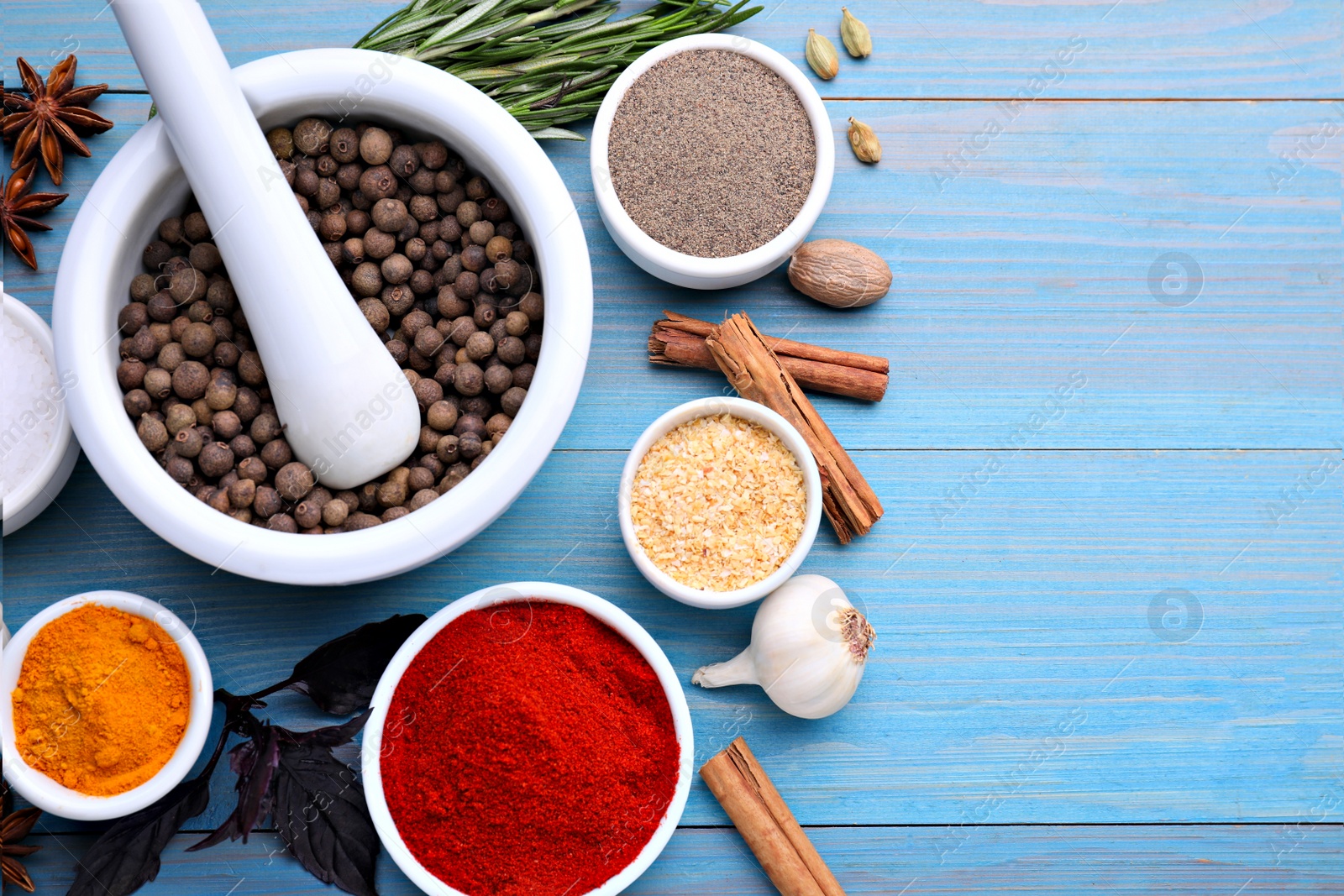 Photo of Flat lay composition with mortar and different spices on light blue wooden table, space for text