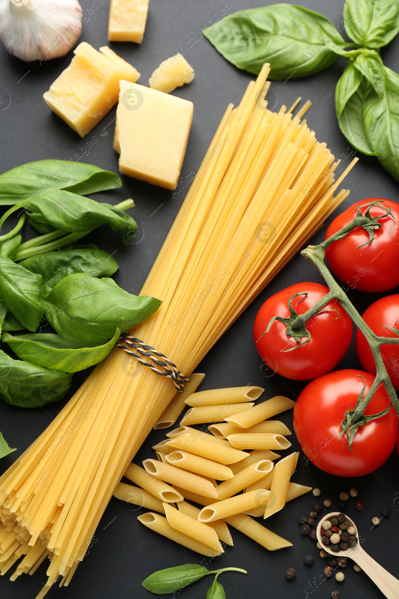 Photo of Different types of pasta, spices and products on black background, flat lay