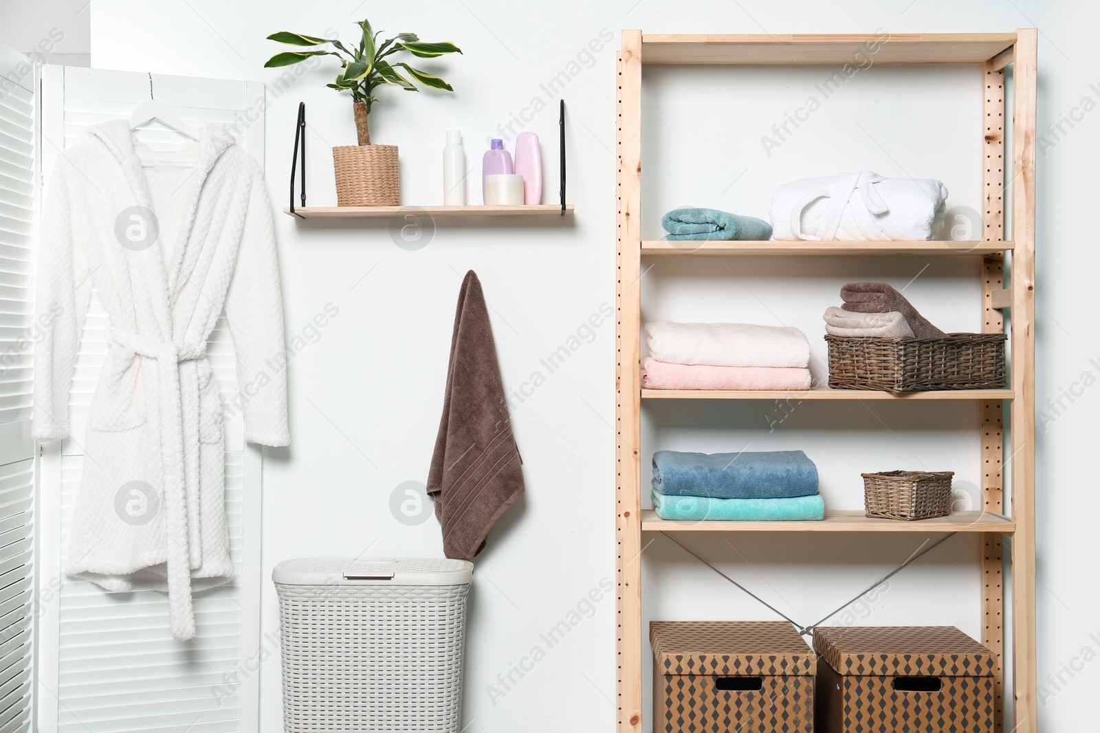 Photo of Clean towels and robe near white wall in modern bathroom interior