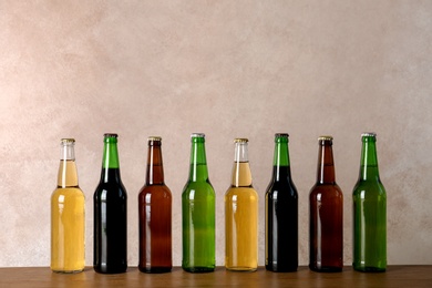 Photo of Bottles with different beer on table against color background