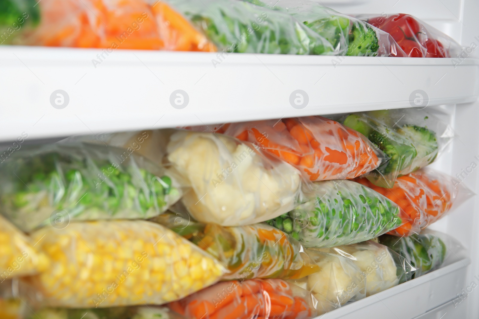 Photo of Plastic bags with deep frozen vegetables in refrigerator