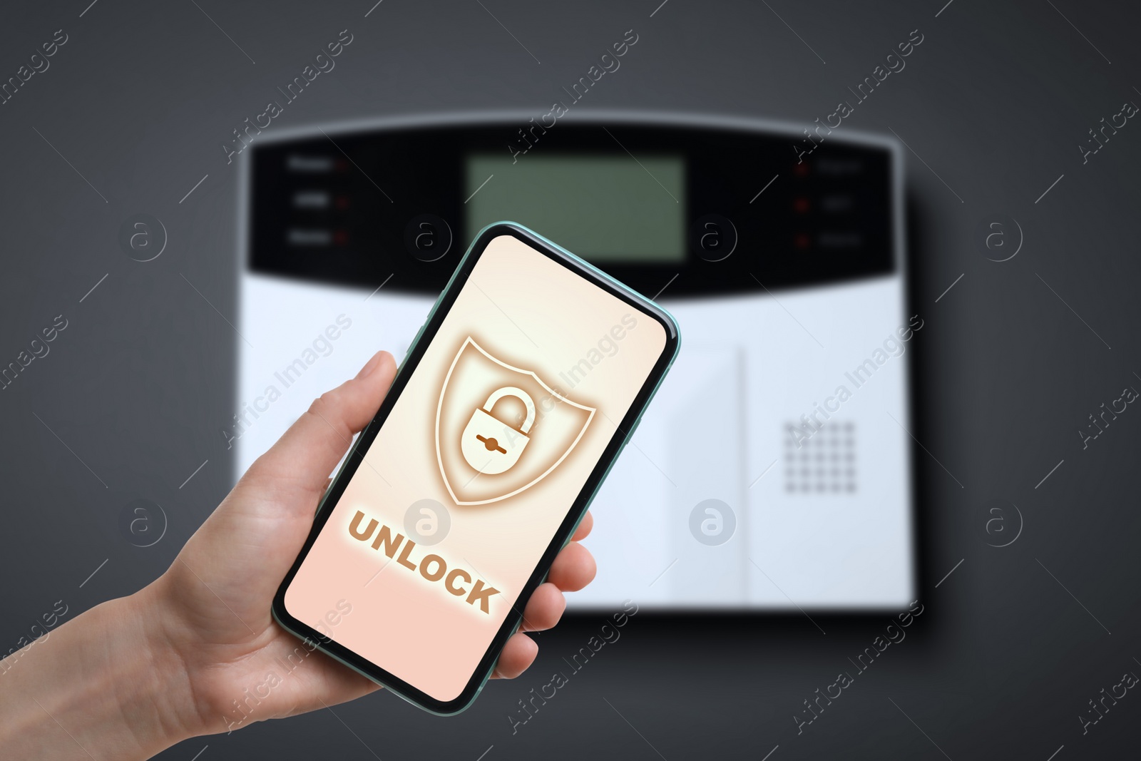 Image of Woman operating home alarm system via mobile phone against dark wall with security control panel, closeup. Application interface on device screen