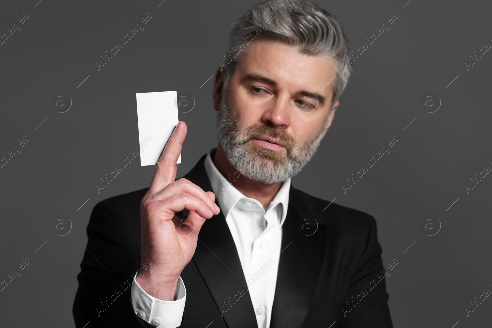 Photo of Handsome businessman holding blank business card on grey background