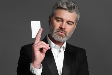 Handsome businessman holding blank business card on grey background