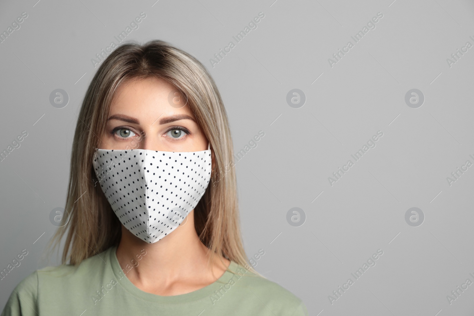 Photo of Young woman in protective face mask on light grey background. Space for text