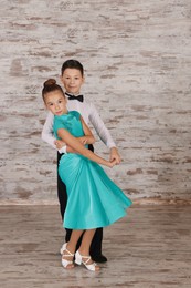 Photo of Beautifully dressed couple of kids dancing together in studio