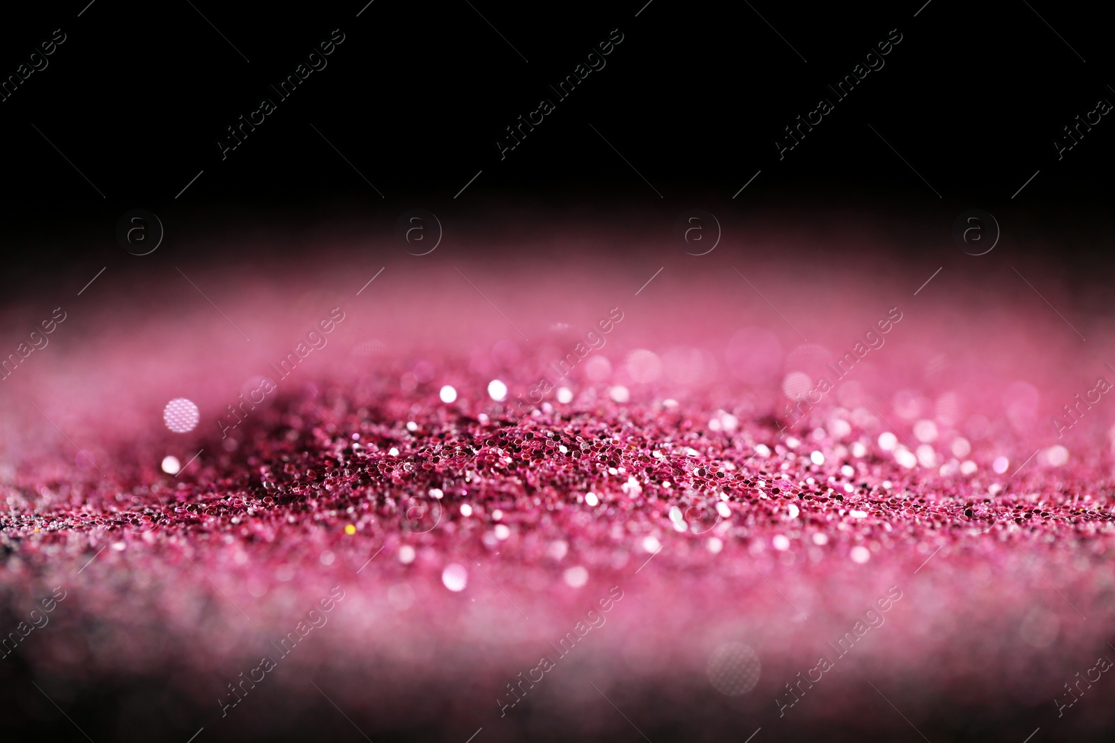 Photo of Heap of rose glitter with bokeh effect on black background, closeup