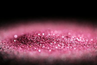 Heap of rose glitter with bokeh effect on black background, closeup