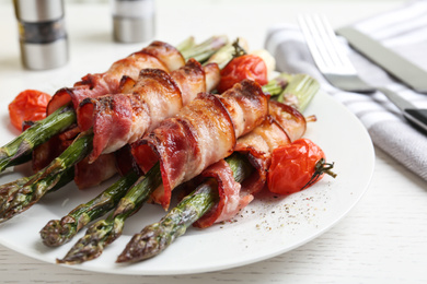 Oven baked asparagus wrapped with bacon on white wooden table, closeup