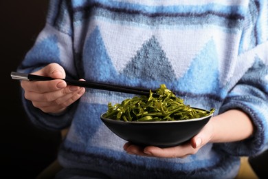 Woman eating fresh laminaria (kelp) seaweed, closeup