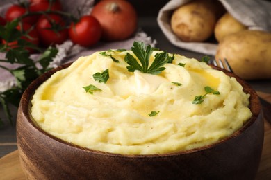 Photo of Bowl of freshly cooked mashed potatoes with parsley on wooden table, closeup