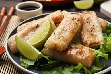 Photo of Tasty fried spring rolls, lettuce and sauce on table, closeup