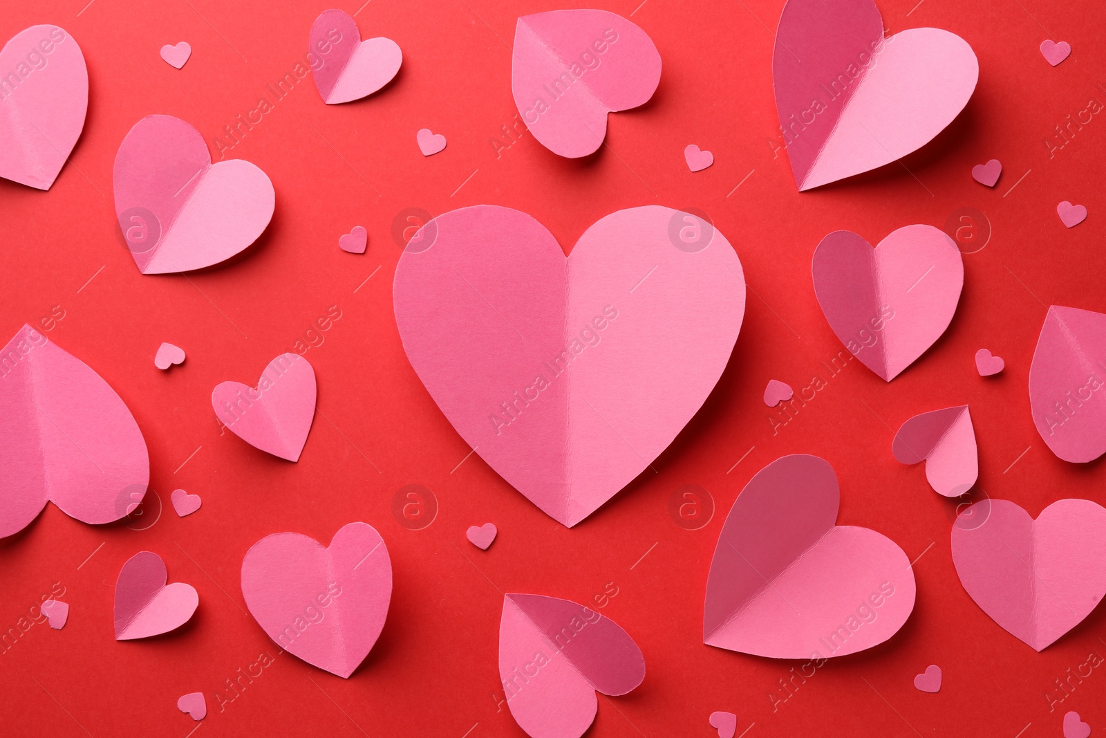 Photo of Pink paper hearts on red background, flat lay