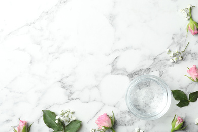 Flat lay composition with cosmetic gel and beautiful flowers on white marble table. Space for text