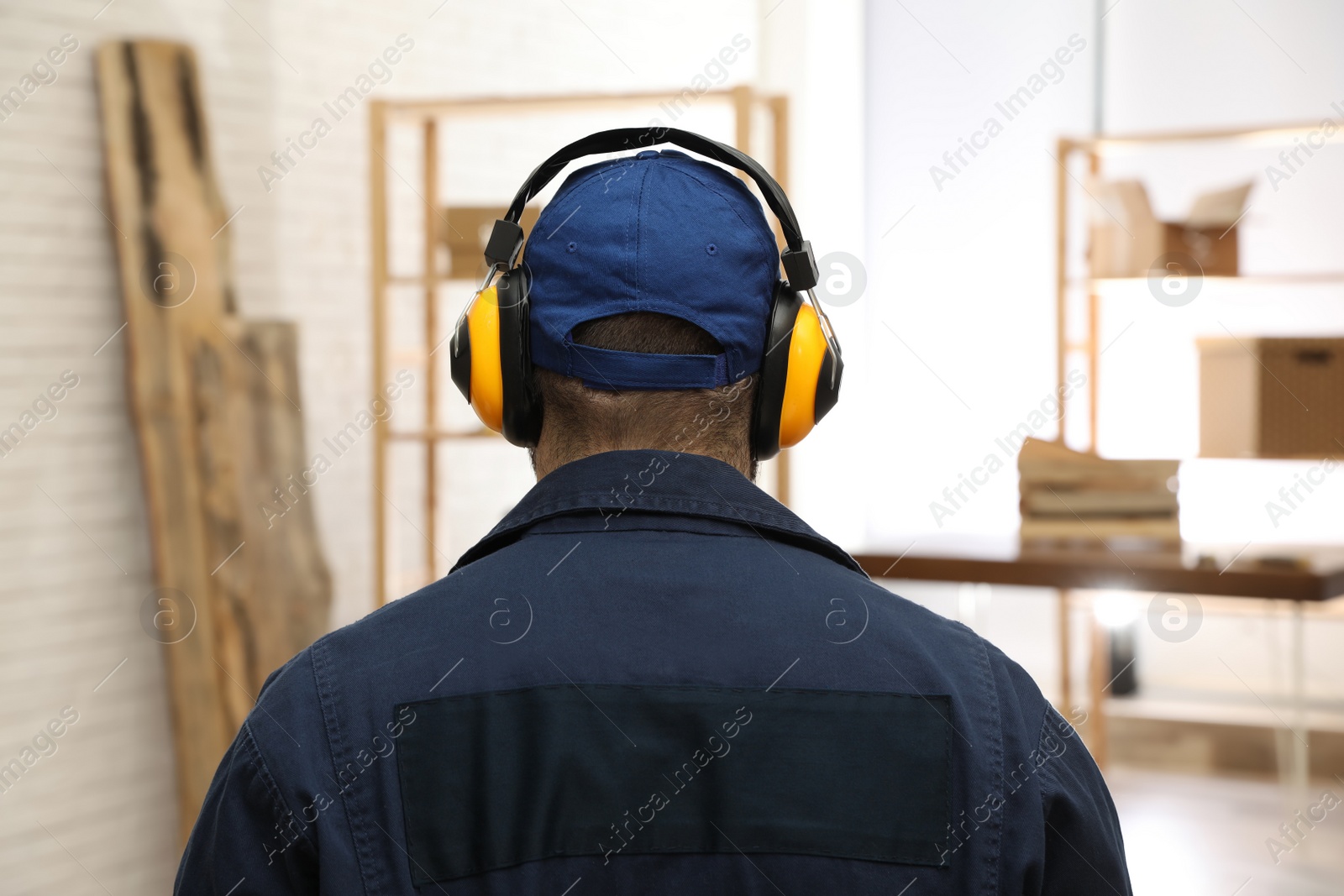 Photo of Worker wearing safety headphones indoors, back view. Hearing protection device