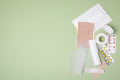 Photo of White bandage and medical supplies on light green background, flat lay. Space for text