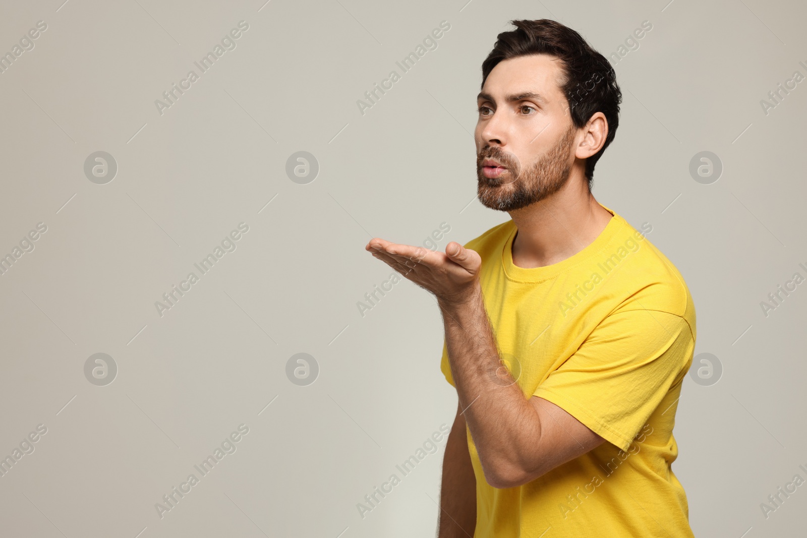 Photo of Handsome man blowing kiss on light grey background. Space for text