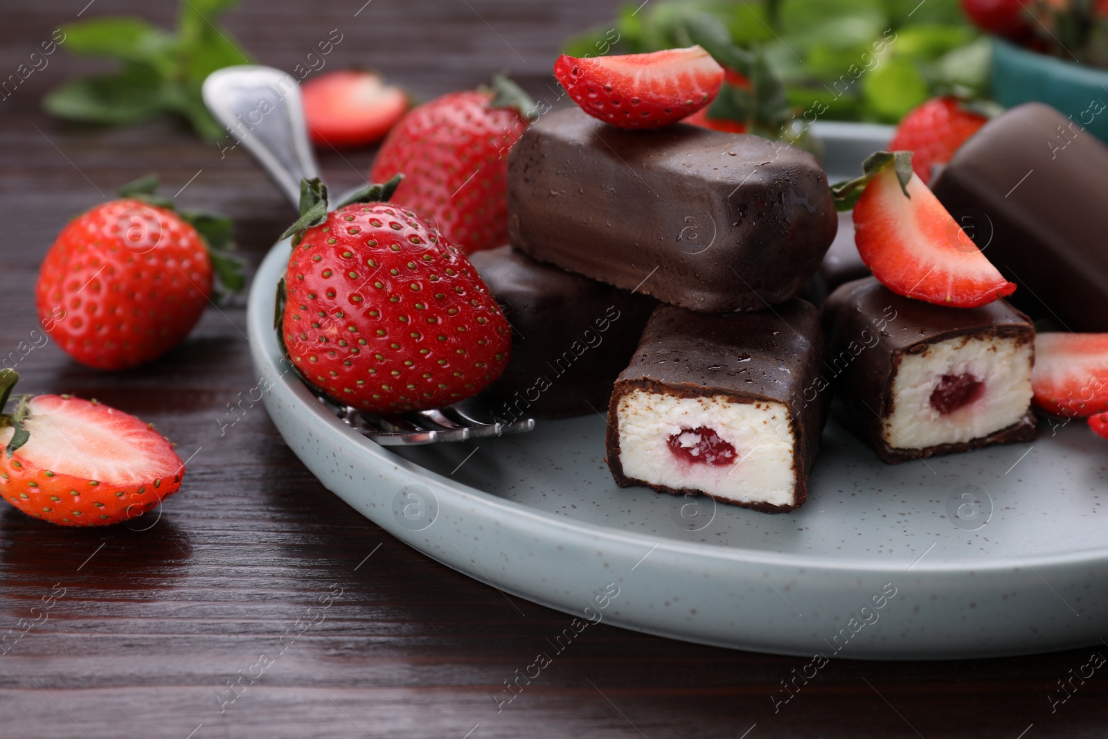 Photo of Delicious glazed curd snacks, mint leaves and fresh strawberries on wooden table, closeup