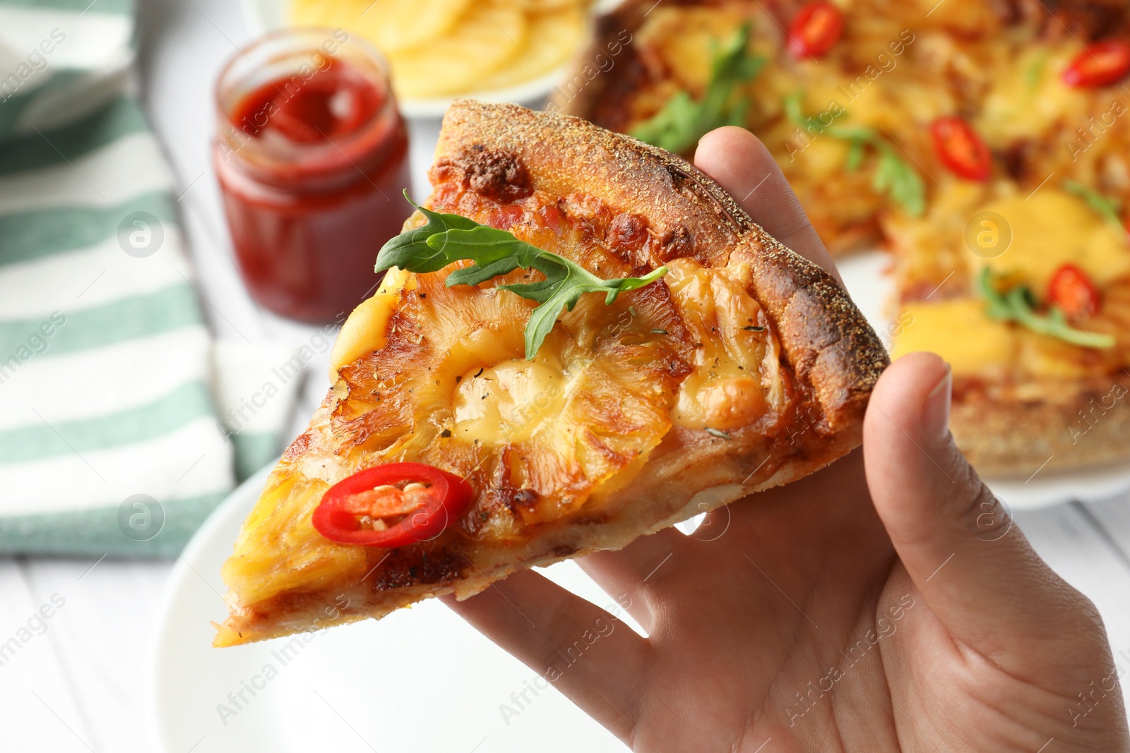 Photo of Woman holding piece of delicious Hawaiian pizza with pineapple, closeup