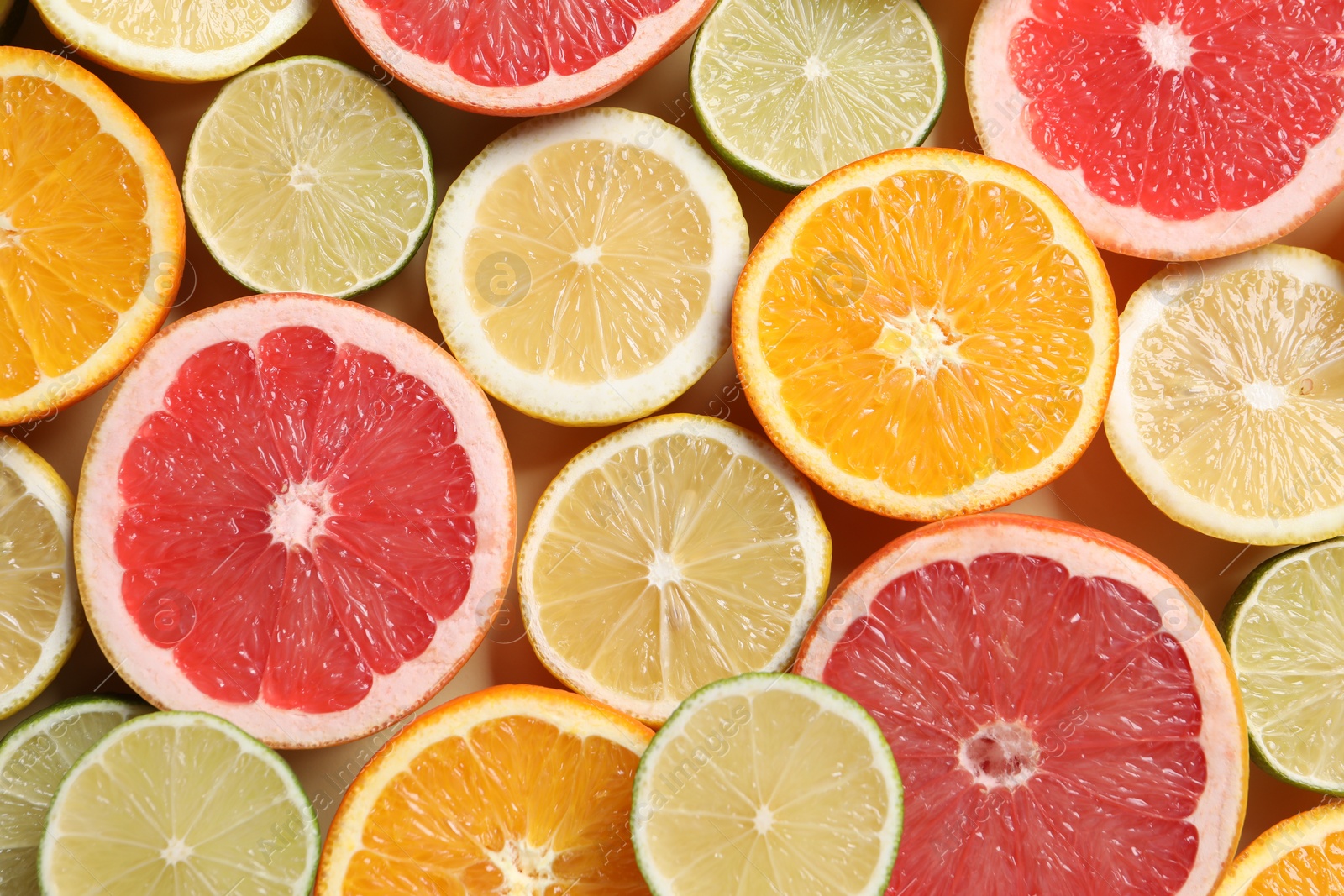 Photo of Different cut citrus fruits on beige table, flat lay