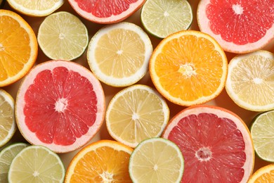 Photo of Different cut citrus fruits on beige table, flat lay