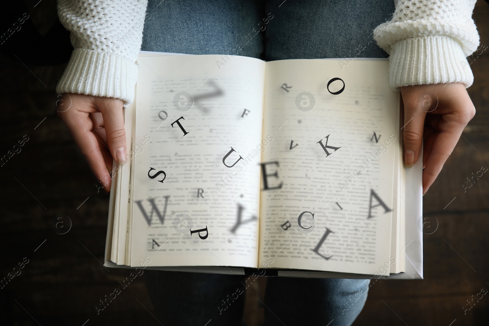 Image of Young woman reading book with letters flying over it indoors, top view