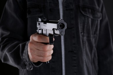 Photo of Man holding gun on black background, closeup
