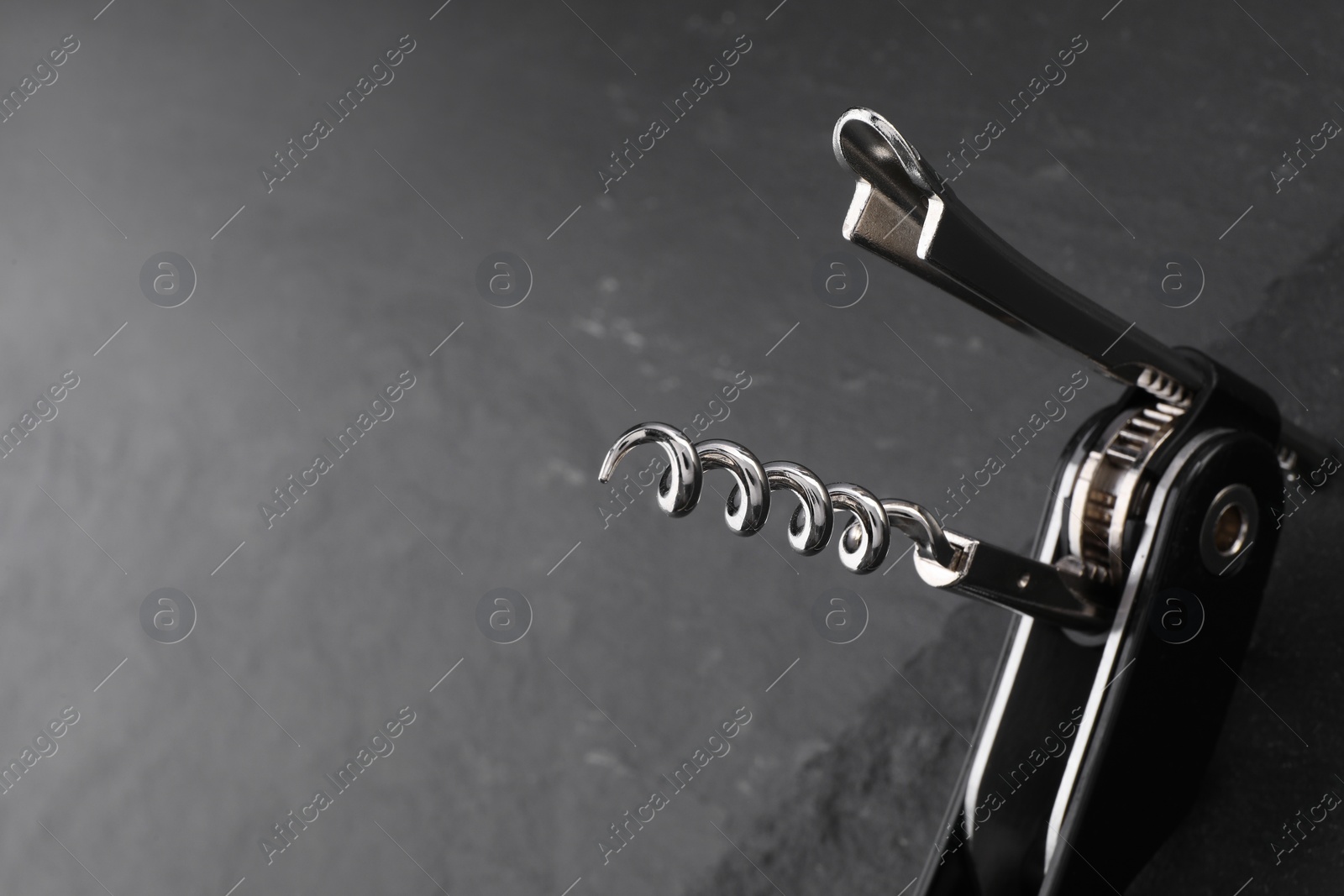 Photo of One corkscrew (sommelier knife) on grey table, closeup. Space for text