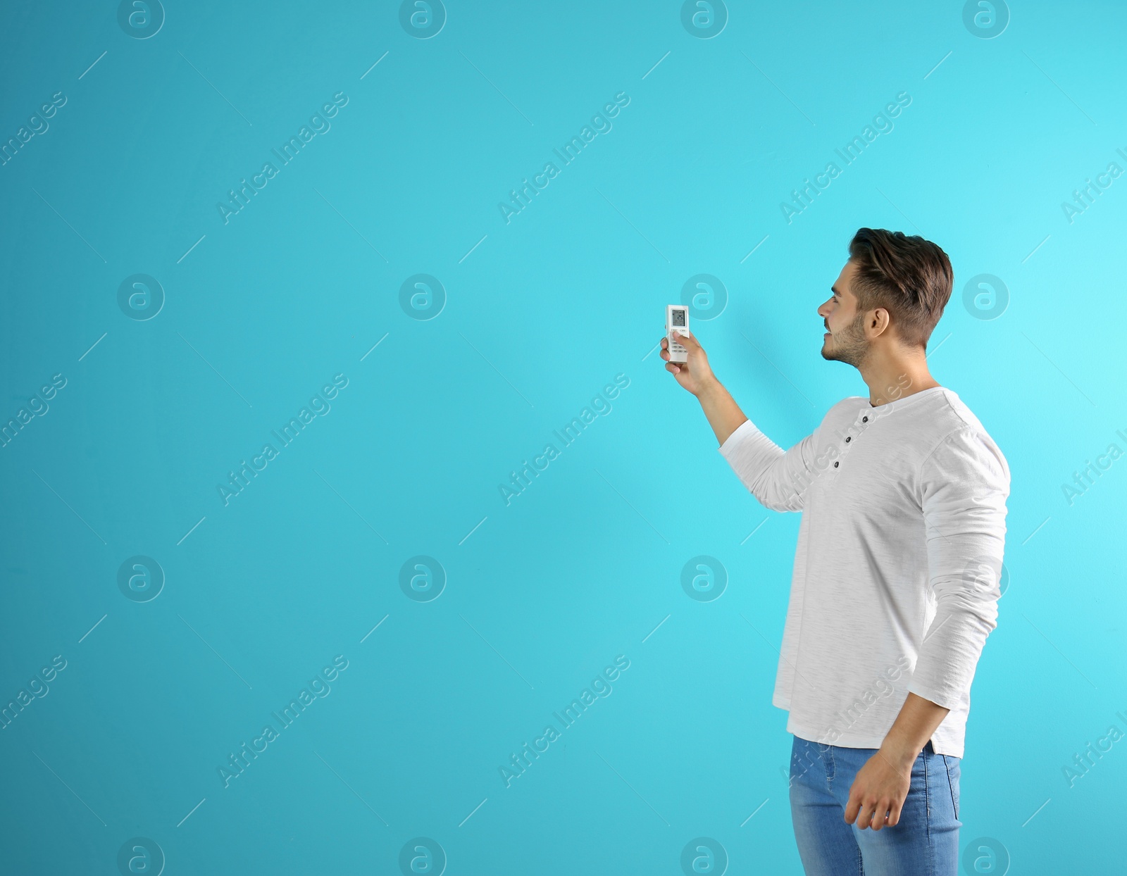 Photo of Young man with air conditioner remote on color background