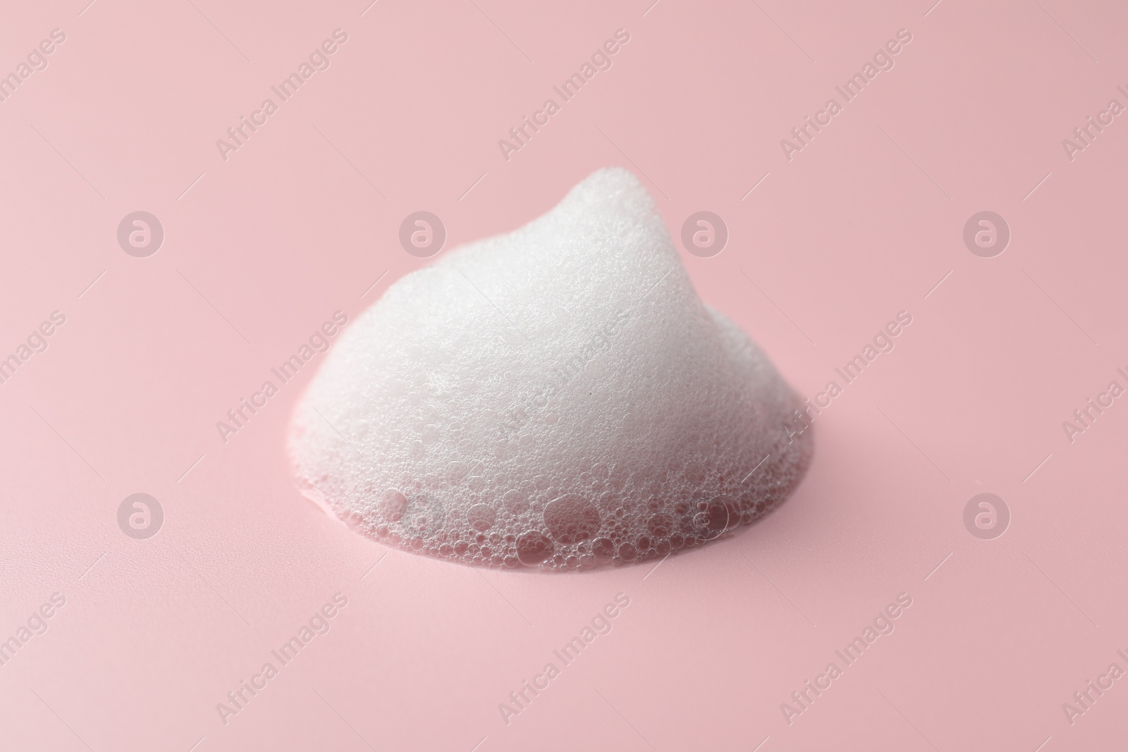 Photo of Drop of fluffy soap foam on pink background