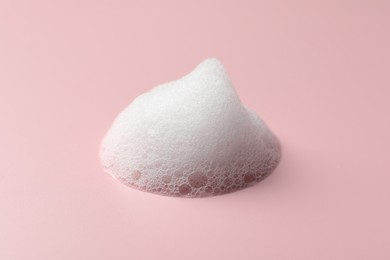 Photo of Drop of fluffy soap foam on pink background