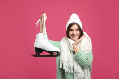 Photo of Emotional woman with ice skates on pink background