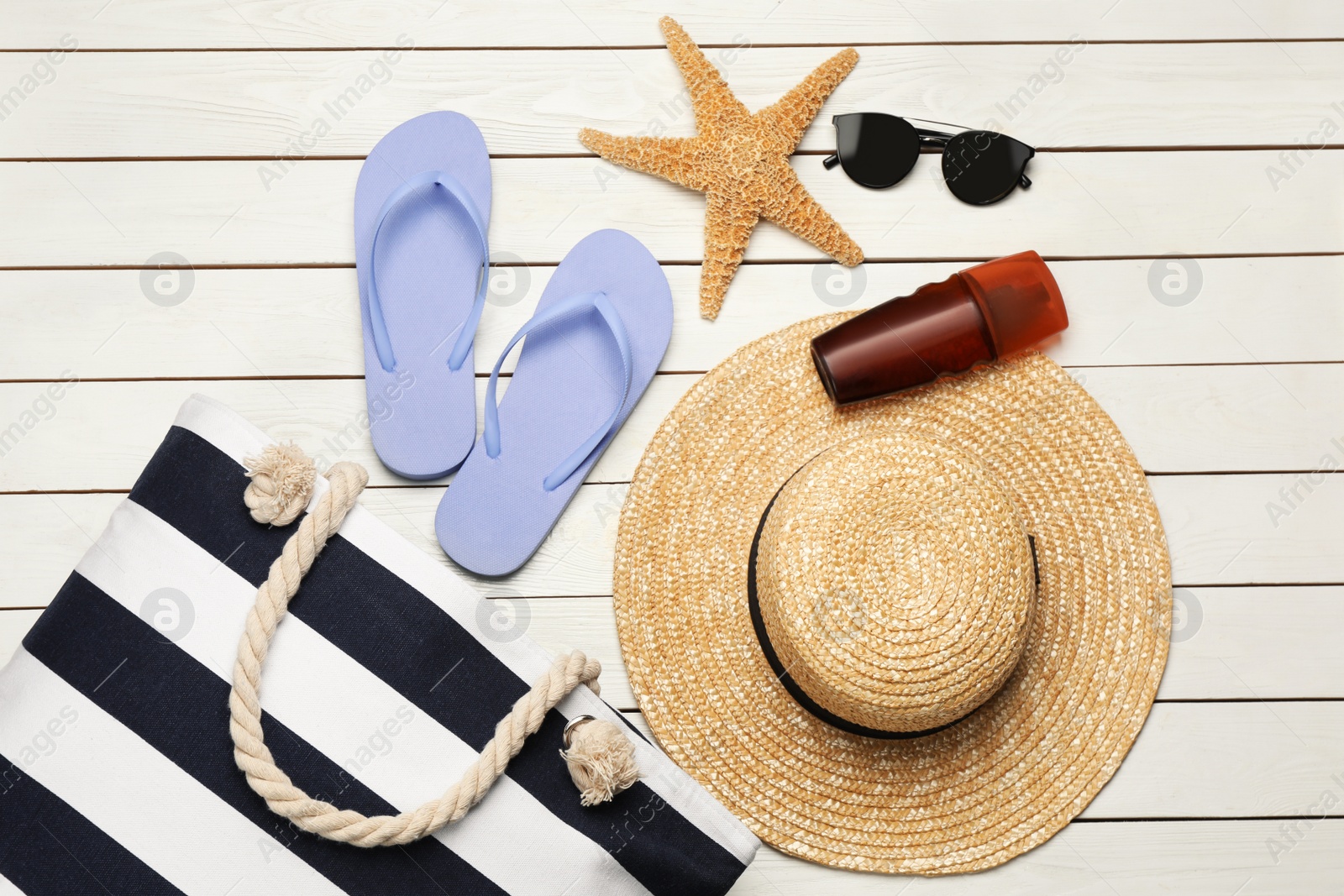 Photo of Stylish bag and beach accessories on white wooden background, flat lay