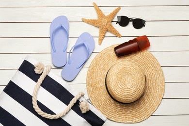 Stylish bag and beach accessories on white wooden background, flat lay