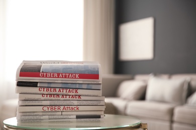 Photo of Stack of newspapers with headlines CYBER ATTACK on table indoors