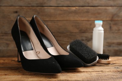 Stylish footwear with shoe care accessories on wooden table