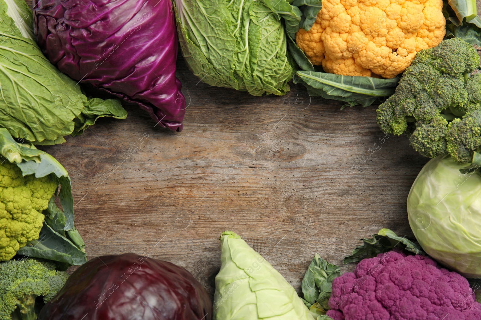 Photo of Different cabbages on wooden table, top view. Healthy food