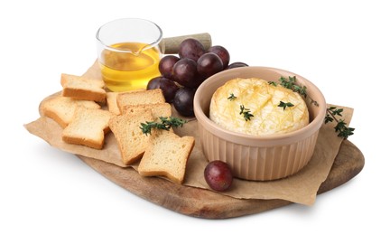 Tasty baked camembert in bowl, croutons, grapes, honey and thyme on white background