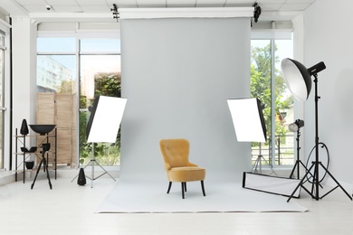 Photo of Interior of modern photo studio with armchair and professional equipment