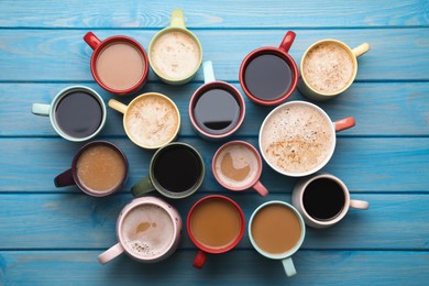 Many cups of different coffee drinks on light blue wooden table, flat lay